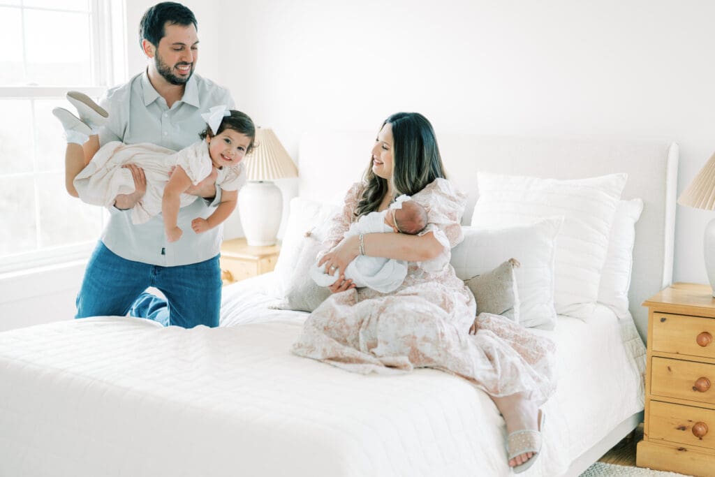 family photo with toddler flying into kiss baby