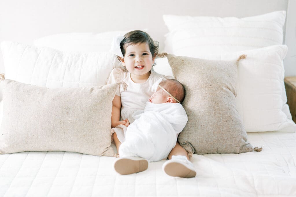 Toddler kissing newborn sibling on the head